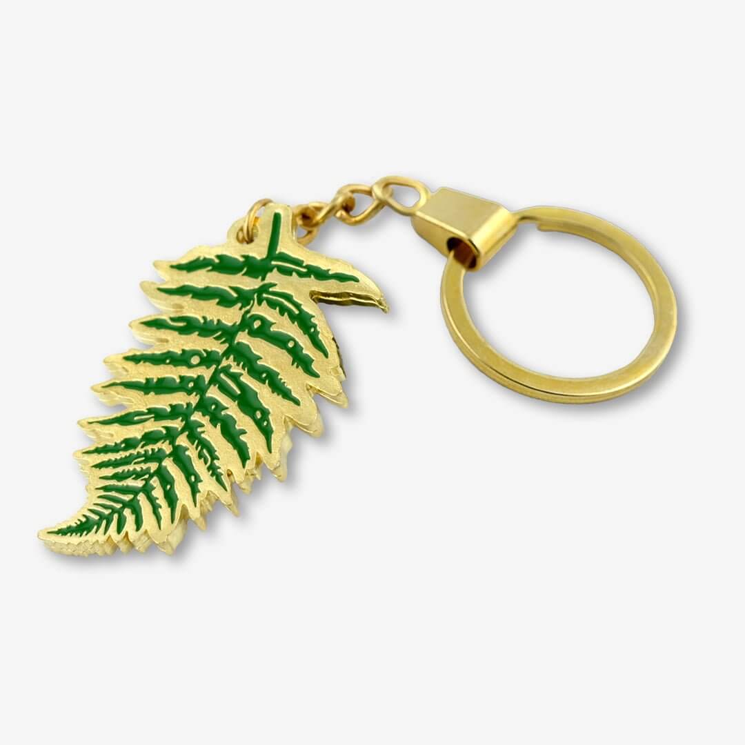 Ręcznie emaliowany brelok do kluczy, liść paproci malowany na zielono w wykończeniu złota błyszczącego metalu od producenta oryginalnych breloków od Pinswear