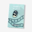 Przypinka Audrey Hepburn w czarnych okularach wpięty na kołnierzyku jeansowej kurtki na zamówienie od producenta pinsów Pinswear
